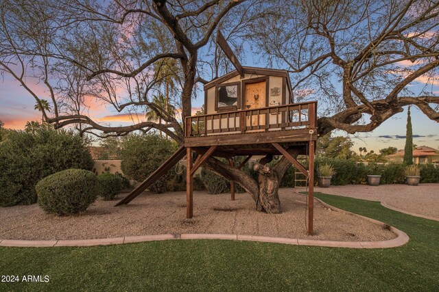 playground at dusk featuring a deck and a yard