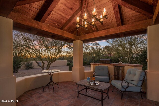 patio terrace at dusk with a gazebo, an outdoor bar, and a grill