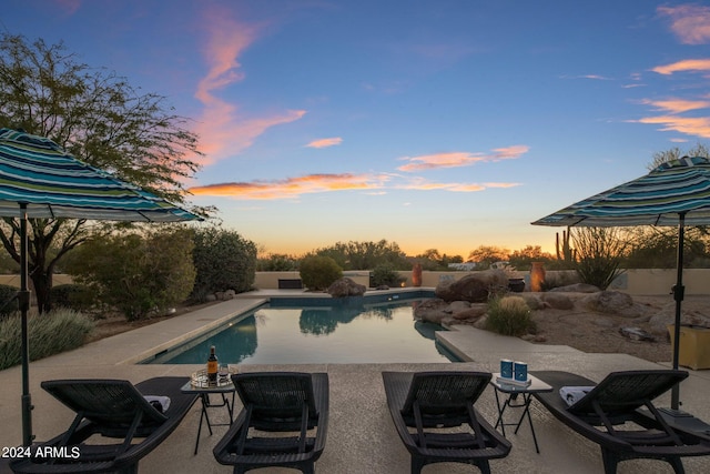 pool at dusk featuring a patio area