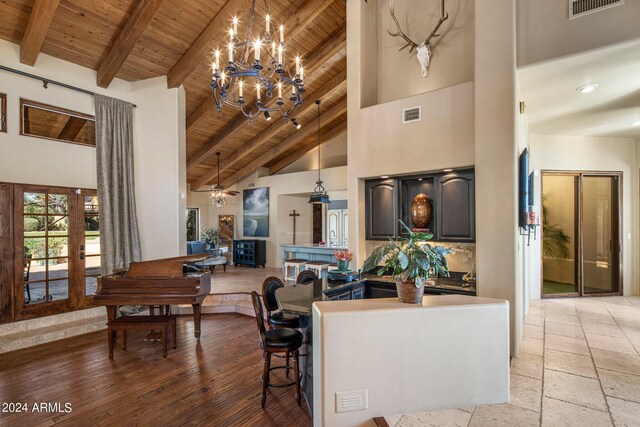 interior space with light hardwood / wood-style floors, high vaulted ceiling, ceiling fan with notable chandelier, wooden ceiling, and beam ceiling