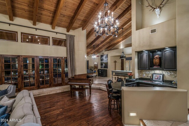 interior space with dark wood-type flooring, beam ceiling, high vaulted ceiling, decorative light fixtures, and wooden ceiling