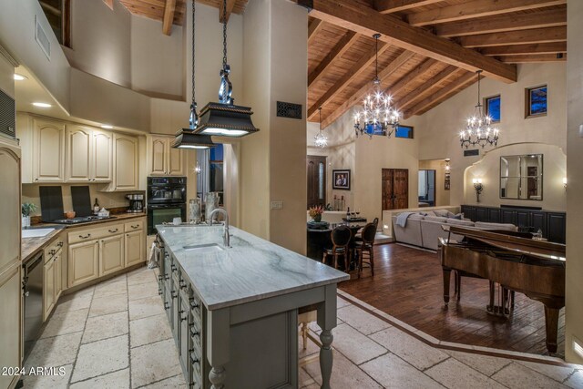 kitchen featuring beamed ceiling, sink, a center island with sink, high vaulted ceiling, and dark stone countertops