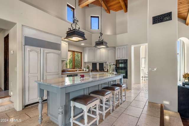 kitchen featuring dobule oven black, paneled refrigerator, high vaulted ceiling, wooden ceiling, and stone tile flooring