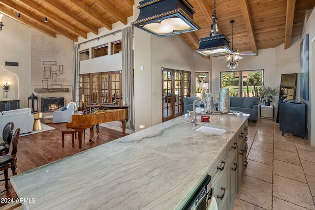 kitchen featuring wooden ceiling, a sink, open floor plan, beam ceiling, and high vaulted ceiling