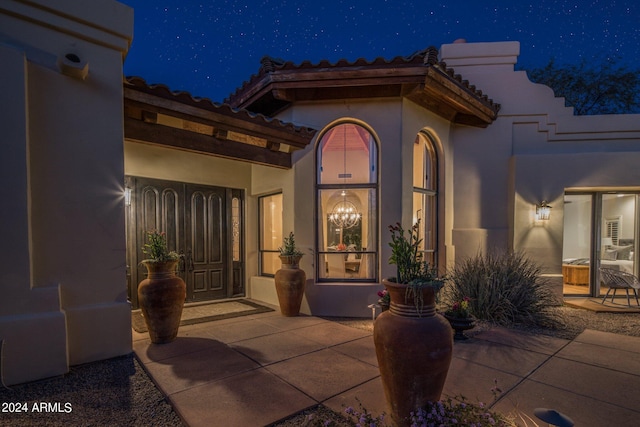 exterior entry at twilight with stucco siding and a tile roof