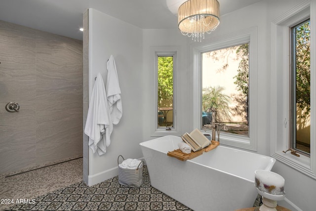 full bathroom featuring a chandelier, a soaking tub, and baseboards