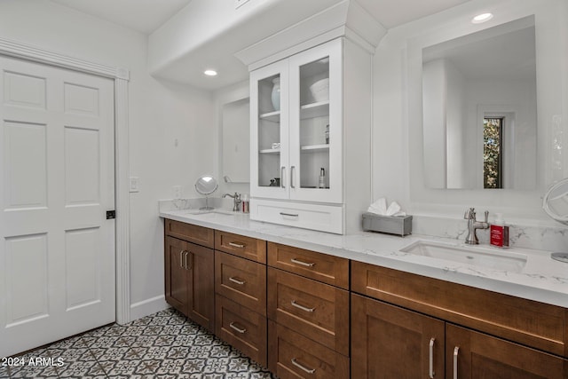 bathroom featuring recessed lighting, double vanity, baseboards, and a sink