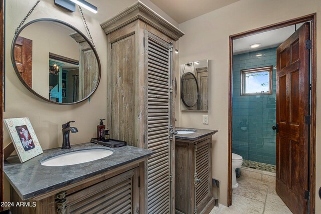 bathroom featuring tiled shower, vanity, and toilet