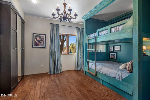 bedroom with wood-type flooring, a notable chandelier, and crown molding