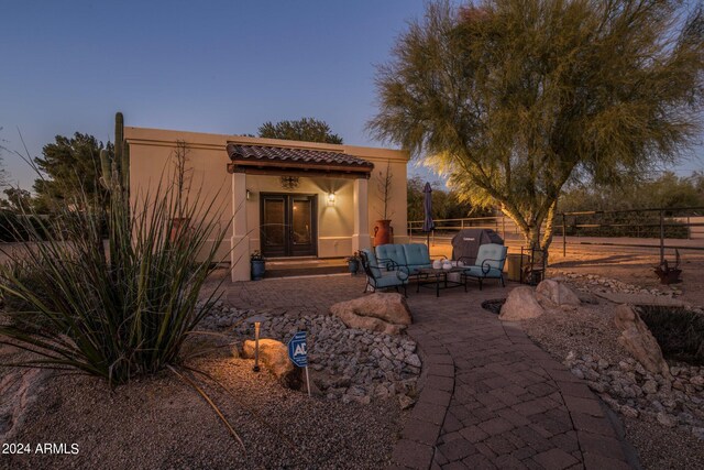 back house at dusk with a patio and outdoor lounge area