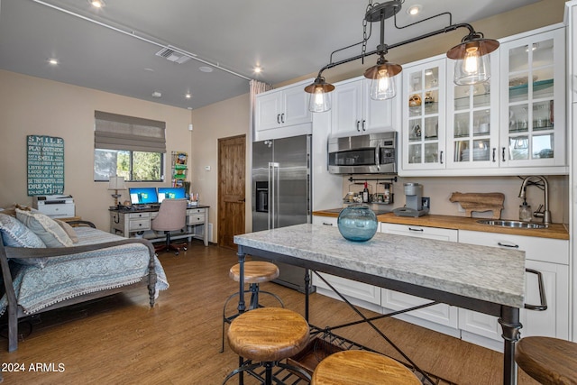 kitchen with visible vents, glass insert cabinets, a sink, white cabinetry, and stainless steel appliances