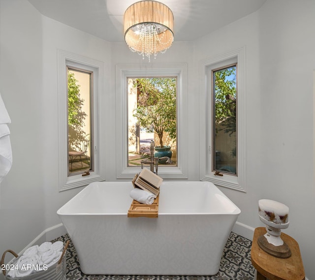 full bathroom with a freestanding tub, an inviting chandelier, and baseboards