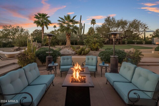 patio terrace at dusk with an outdoor living space with a fire pit