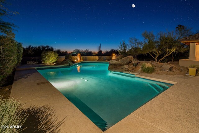 pool at dusk with a patio area