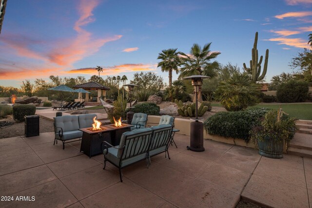 patio terrace at dusk featuring a gazebo and an outdoor living space with a fire pit