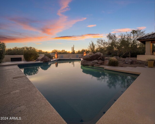 pool at dusk with a patio area