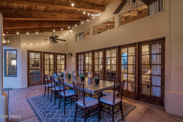 dining space with beamed ceiling, wooden ceiling, a high ceiling, ceiling fan, and french doors