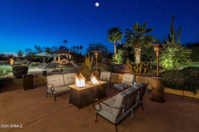 patio at night with an outdoor living space with a fire pit, an outdoor pool, and a gazebo