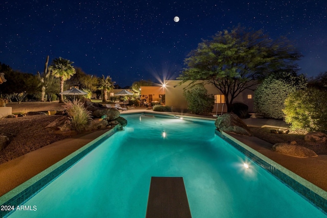pool at twilight with an outdoor pool and a patio