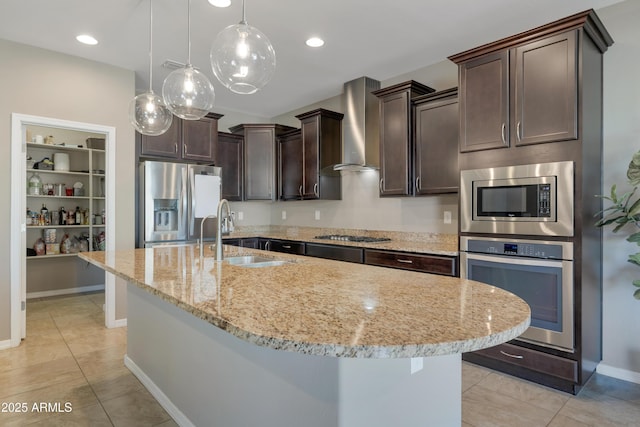 kitchen with appliances with stainless steel finishes, decorative light fixtures, sink, dark brown cabinets, and wall chimney range hood