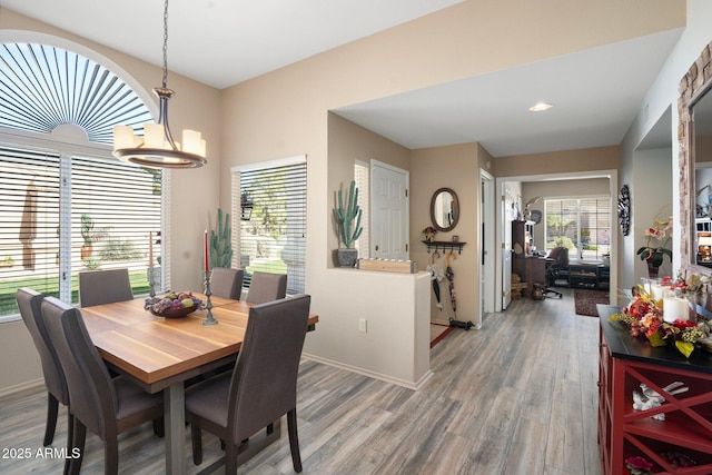 dining space featuring a chandelier, light wood-style flooring, baseboards, and a healthy amount of sunlight