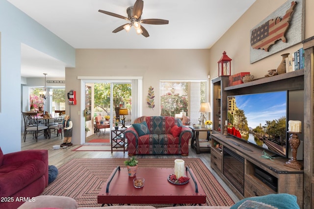 living area featuring ceiling fan with notable chandelier and wood finished floors