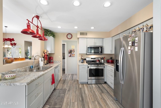 kitchen with visible vents, light countertops, wood finished floors, stainless steel appliances, and a sink