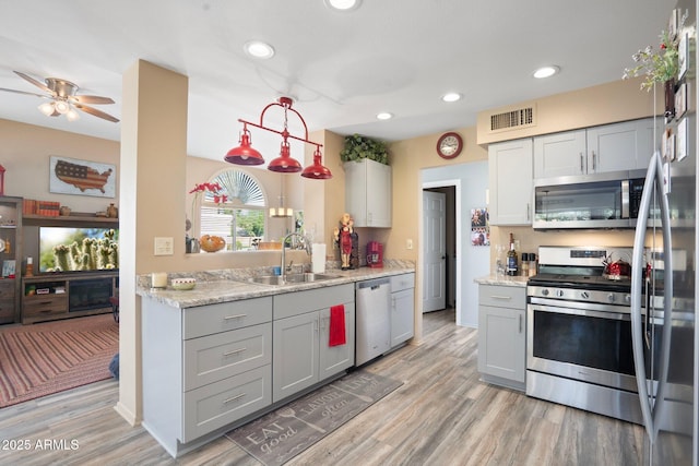 kitchen with visible vents, light wood finished floors, a sink, gray cabinetry, and stainless steel appliances