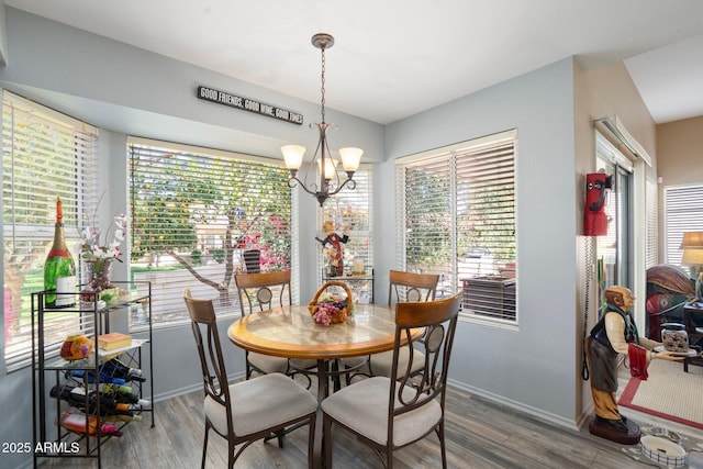 dining area with baseboards, an inviting chandelier, wood finished floors, and a healthy amount of sunlight