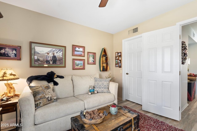 living room featuring visible vents, baseboards, ceiling fan, and wood finished floors