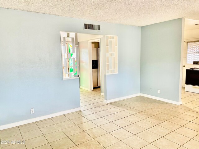 unfurnished room with light tile patterned floors and a textured ceiling