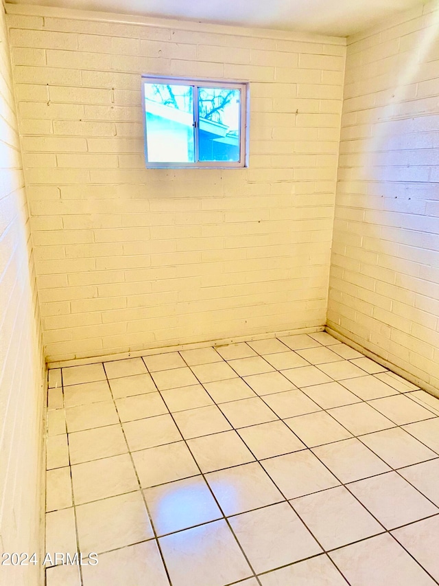 spare room with light tile patterned floors and brick wall