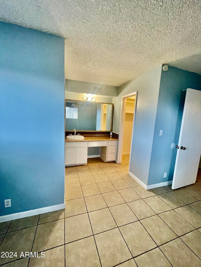 interior space with light tile patterned flooring, sink, and a textured ceiling