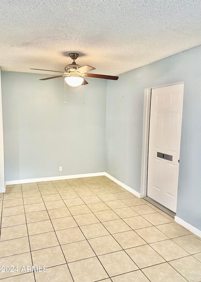 empty room featuring ceiling fan, light tile patterned flooring, and a textured ceiling