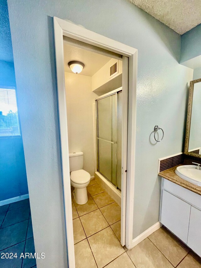 bathroom with toilet, vanity, tile patterned floors, and walk in shower