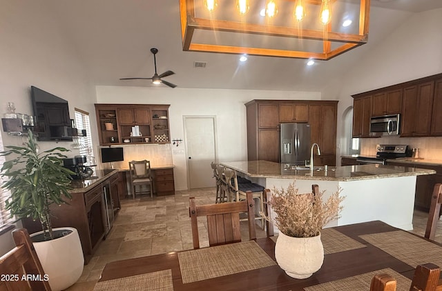 10029 S 44th St, Phoenix, AZ 85044 - kitchen with appliances with stainless steel finishes, tasteful backsplash, an island with sink, open shelves, and high vaulted ceiling