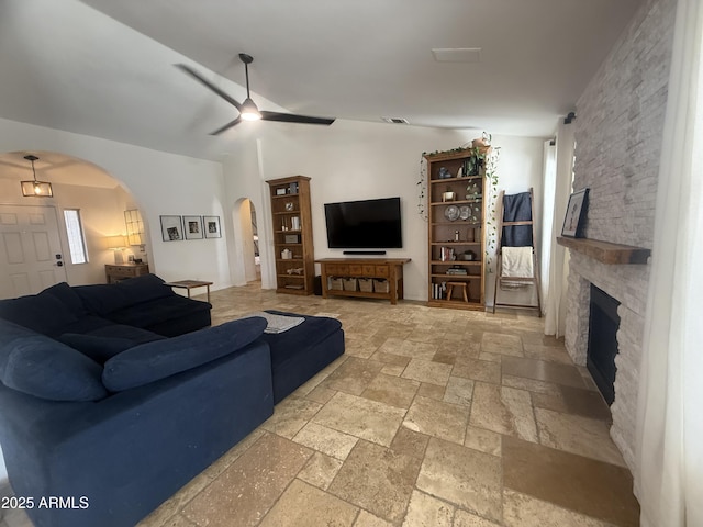 10029 S 44th St, Phoenix, AZ 85044 - living room featuring arched walkways, ceiling fan, stone tile floors, vaulted ceiling, and a stone fireplace