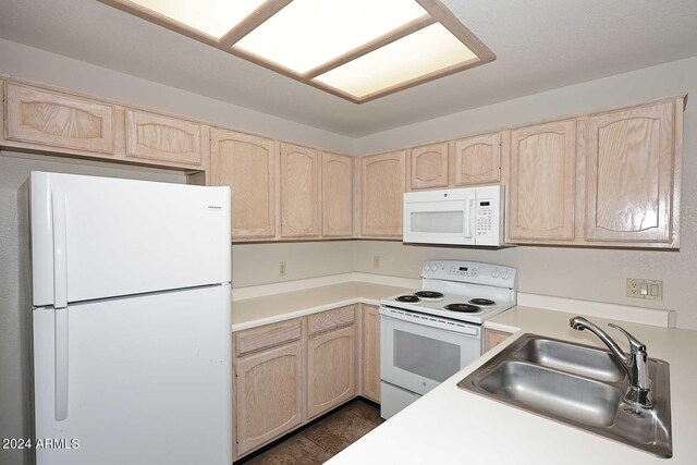 kitchen featuring white appliances, light brown cabinetry, dark tile patterned flooring, and sink