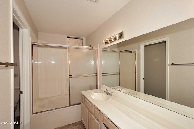 full bathroom with toilet, bath / shower combo with glass door, and vanity