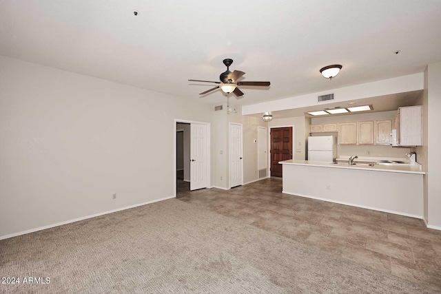 unfurnished living room with sink, ceiling fan, and dark colored carpet