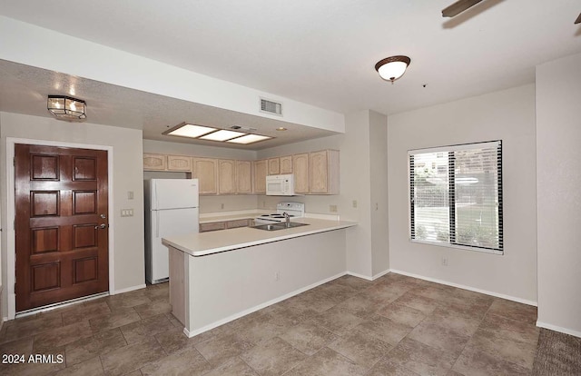 kitchen with white appliances, kitchen peninsula, light brown cabinetry, and sink