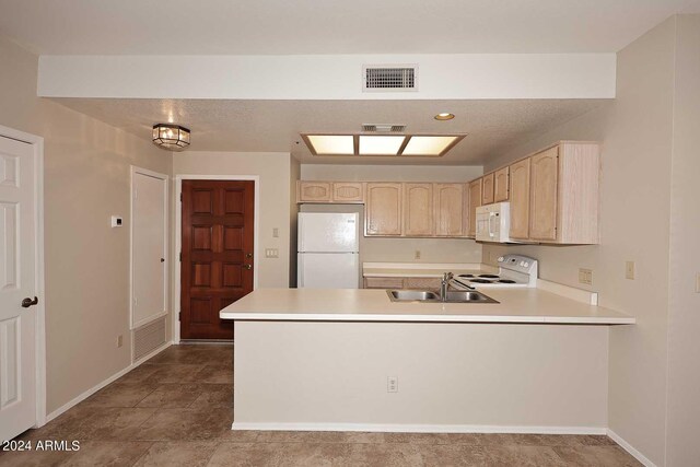 kitchen featuring sink, white appliances, light brown cabinetry, and kitchen peninsula