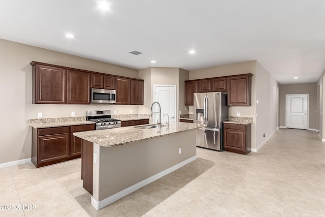 kitchen with a kitchen island with sink, sink, stainless steel appliances, and dark brown cabinets