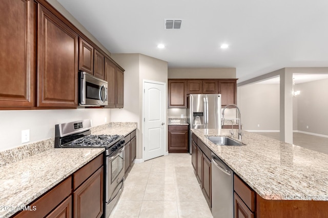 kitchen with a center island with sink, sink, appliances with stainless steel finishes, light tile patterned flooring, and a chandelier