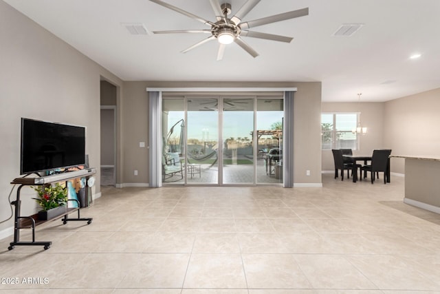 tiled living room featuring ceiling fan with notable chandelier