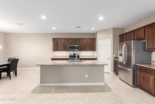 kitchen featuring a center island with sink, dark brown cabinetry, sink, and appliances with stainless steel finishes