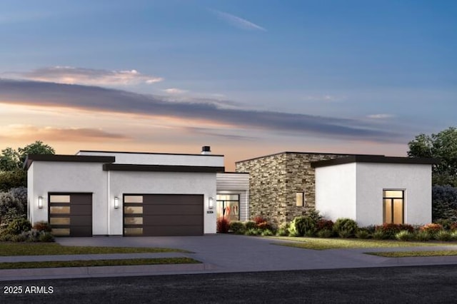 contemporary home featuring stone siding, concrete driveway, an attached garage, and stucco siding