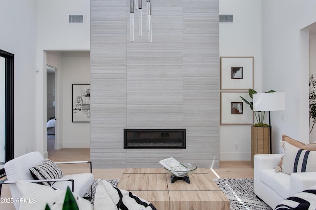 living room featuring visible vents, a fireplace, baseboards, and wood finished floors