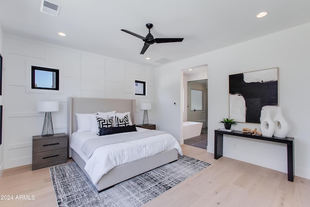 bedroom featuring connected bathroom, light wood-style flooring, a decorative wall, recessed lighting, and visible vents