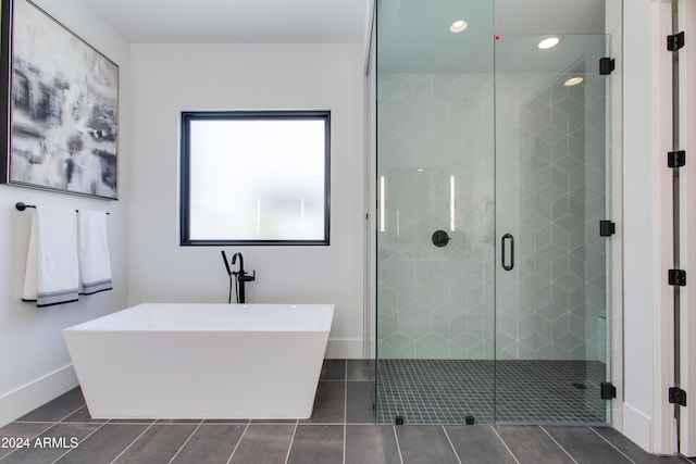 bathroom featuring a freestanding tub, tile patterned flooring, baseboards, and a shower stall